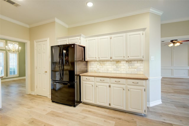 kitchen with black fridge, white cabinets, ornamental molding, and backsplash