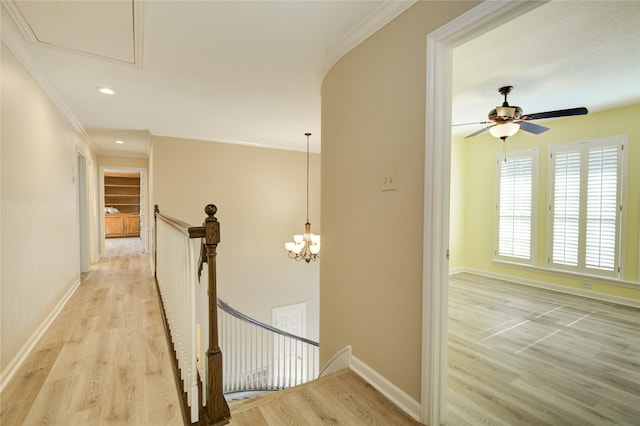 hall featuring an inviting chandelier, ornamental molding, and light hardwood / wood-style flooring