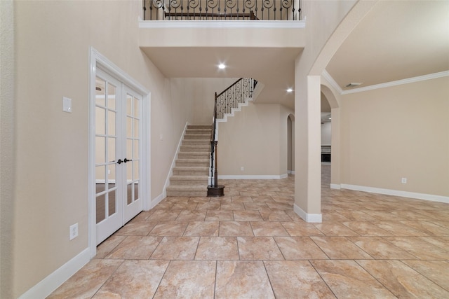 foyer entrance featuring ornamental molding, french doors, and a high ceiling