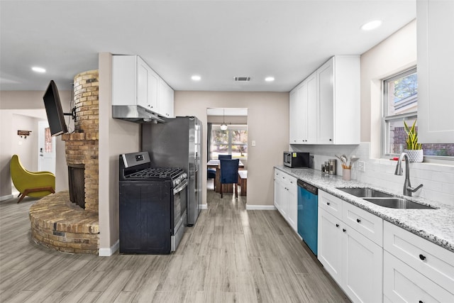 kitchen featuring sink, white cabinets, light stone counters, stainless steel appliances, and light wood-type flooring