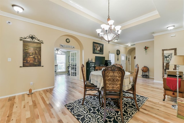 dining space featuring ceiling fan with notable chandelier, ornamental molding, a tray ceiling, and hardwood / wood-style floors