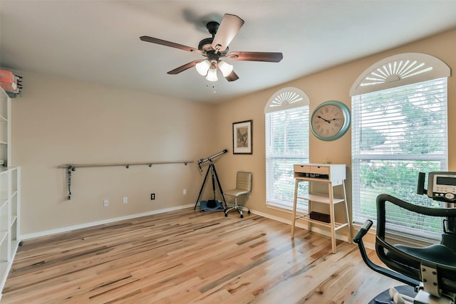 exercise room featuring ceiling fan, light wood-type flooring, and plenty of natural light