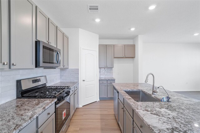 8203 Leisure Point Dr, Cypress, TX 77433 - kitchen with appliances with stainless steel finishes, gray cabinetry, a sink, light wood-type flooring, and recessed lighting
