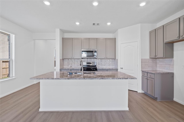 8203 Leisure Point Dr, Cypress, TX 77433 - kitchen featuring appliances with stainless steel finishes, gray cabinets, light stone countertops, light wood-type flooring, and recessed lighting