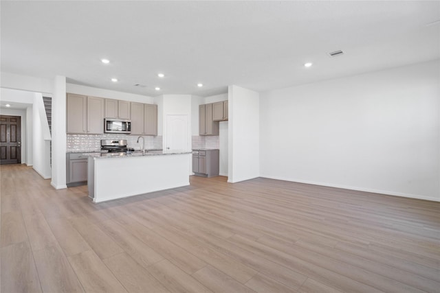 8203 Leisure Point Dr, Cypress, TX 77433 - kitchen with stainless steel appliances, backsplash, recessed lighting, light wood-style floors, and an island with sink