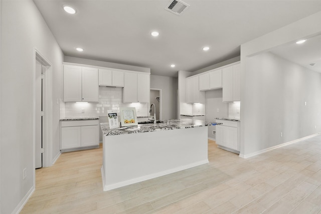 kitchen with white cabinetry and a center island with sink