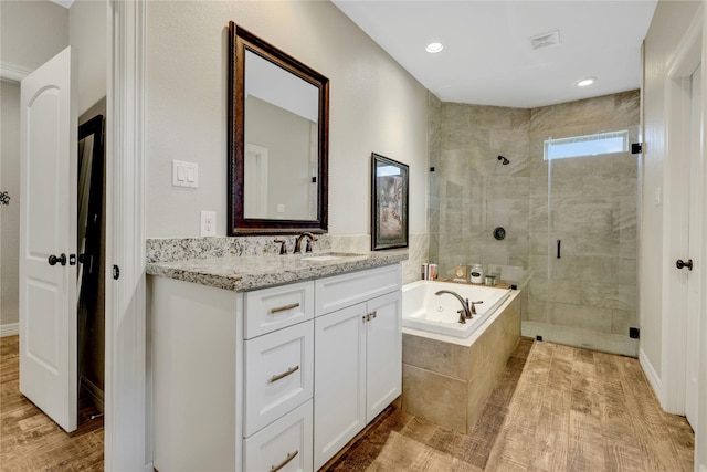 bathroom with independent shower and bath, hardwood / wood-style flooring, and vanity