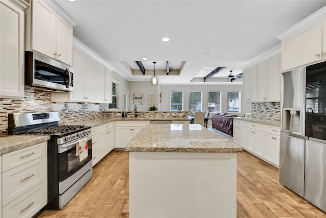 kitchen with white cabinets, appliances with stainless steel finishes, a kitchen island, hanging light fixtures, and kitchen peninsula