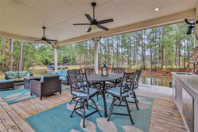 deck with an outdoor living space, sink, a water view, and ceiling fan