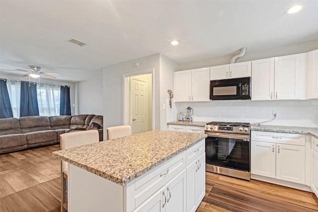 kitchen with white cabinetry, light wood-type flooring, gas range, and a kitchen island