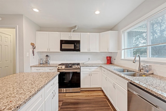 kitchen with stainless steel appliances, white cabinetry, sink, and hardwood / wood-style flooring