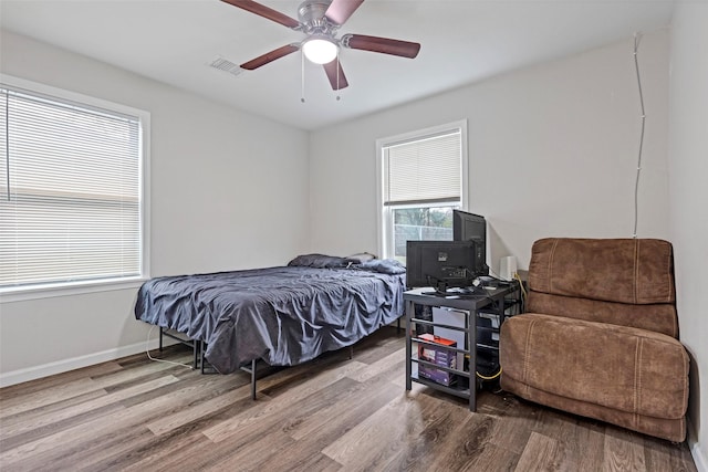 bedroom with ceiling fan, wood-type flooring, and multiple windows