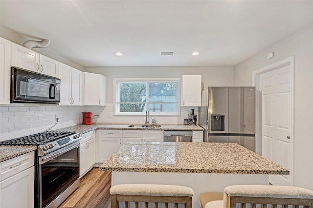 kitchen featuring appliances with stainless steel finishes, a kitchen breakfast bar, white cabinetry, and sink