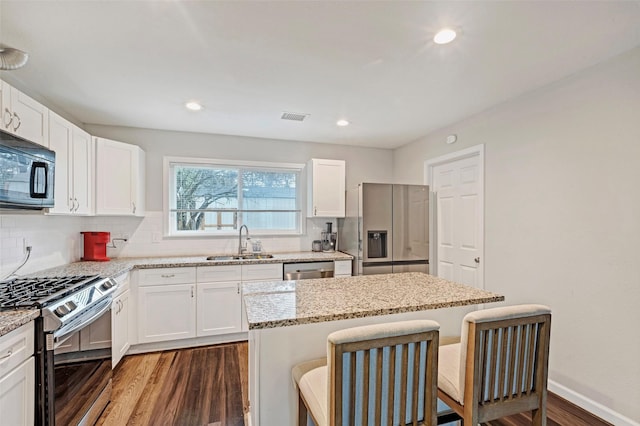 kitchen featuring sink, white cabinetry, a kitchen breakfast bar, a kitchen island, and appliances with stainless steel finishes