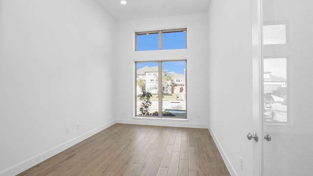 spare room with light hardwood / wood-style flooring and a towering ceiling