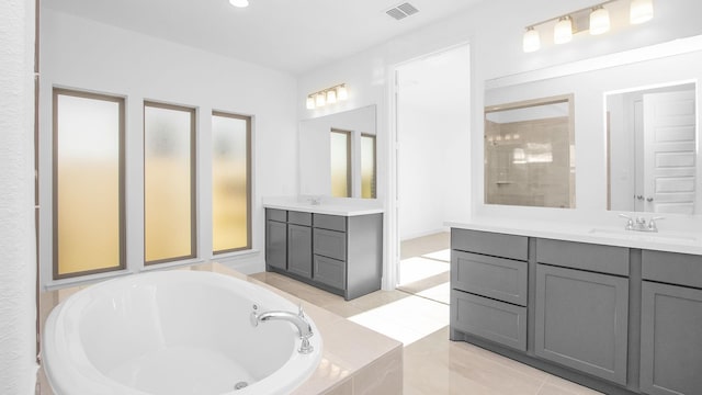 bathroom with tile patterned flooring, a relaxing tiled tub, and vanity