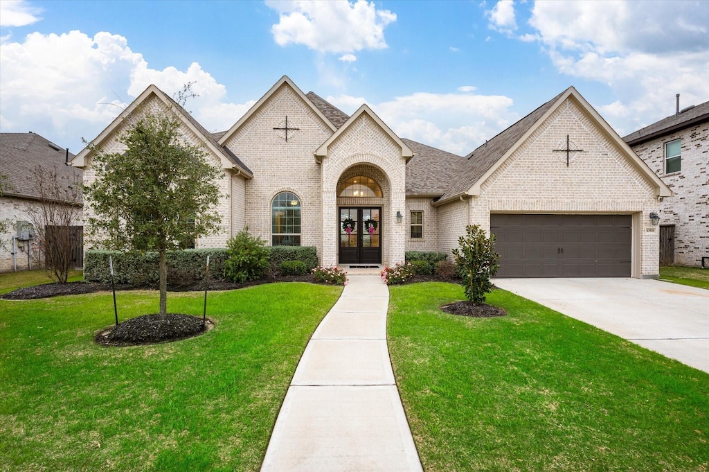 french country style house with french doors, a front yard, and a garage