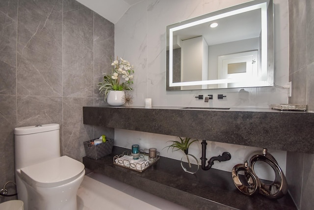 bathroom featuring sink, tile walls, vaulted ceiling, and toilet