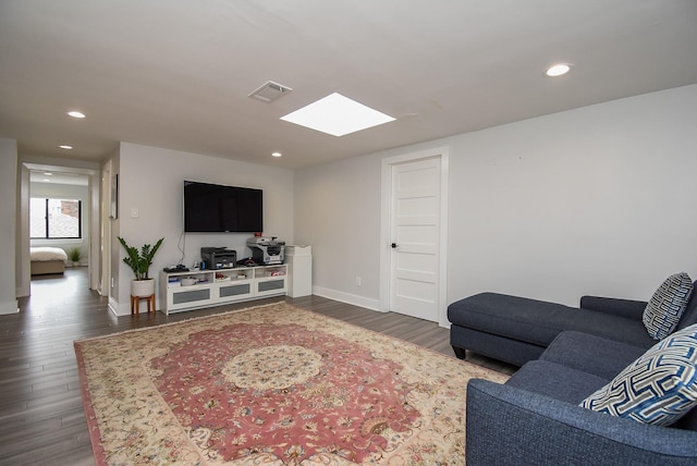 living room featuring dark hardwood / wood-style flooring and a skylight