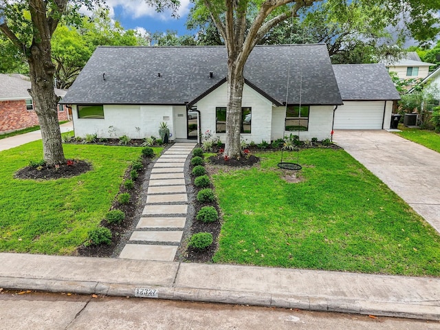 view of front of house featuring a garage, cooling unit, and a front yard