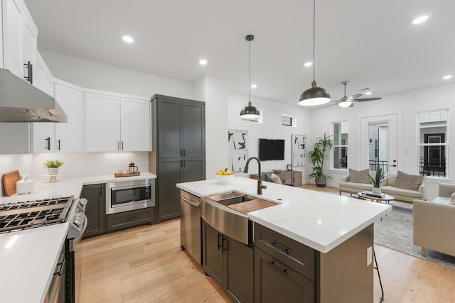 kitchen with pendant lighting, ceiling fan, appliances with stainless steel finishes, sink, and white cabinets