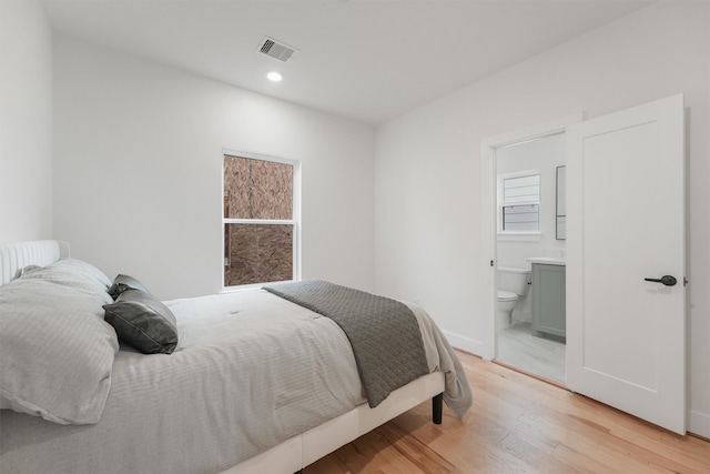 bedroom with ensuite bath and light wood-type flooring