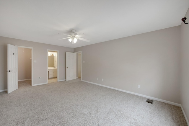 unfurnished bedroom with ensuite bath, ceiling fan, and light carpet