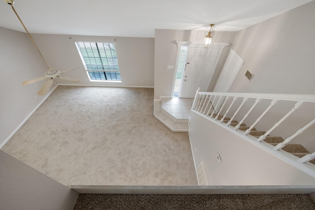 foyer with ceiling fan with notable chandelier and light colored carpet