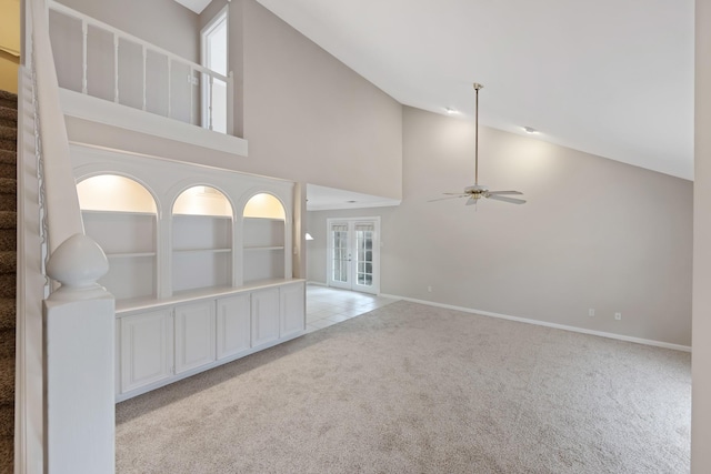 unfurnished living room with light colored carpet, plenty of natural light, and high vaulted ceiling