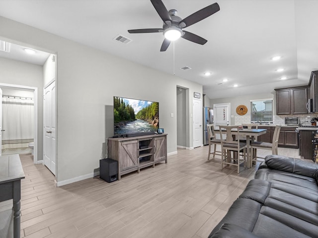 living room with ceiling fan and light wood-type flooring