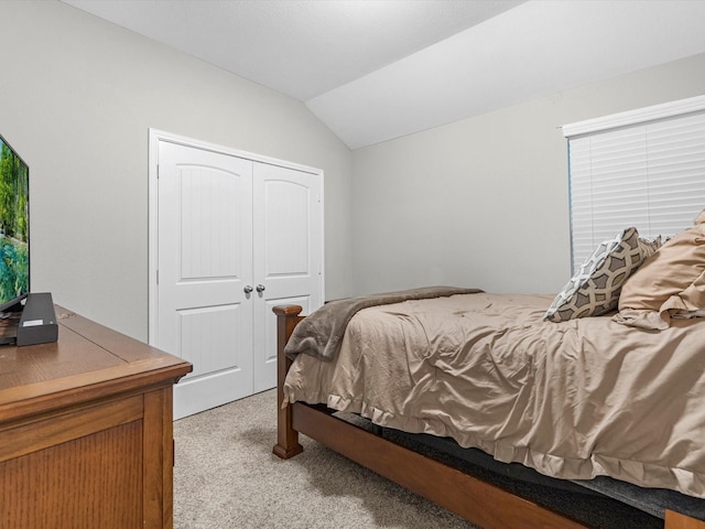 bedroom featuring a closet, vaulted ceiling, and light colored carpet