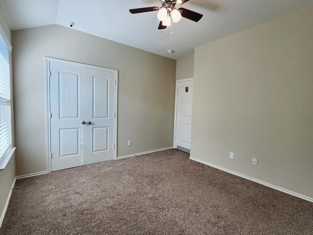 unfurnished bedroom with ceiling fan, lofted ceiling, dark carpet, and a closet