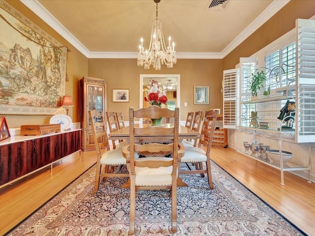 dining space featuring an inviting chandelier, crown molding, and light hardwood / wood-style flooring