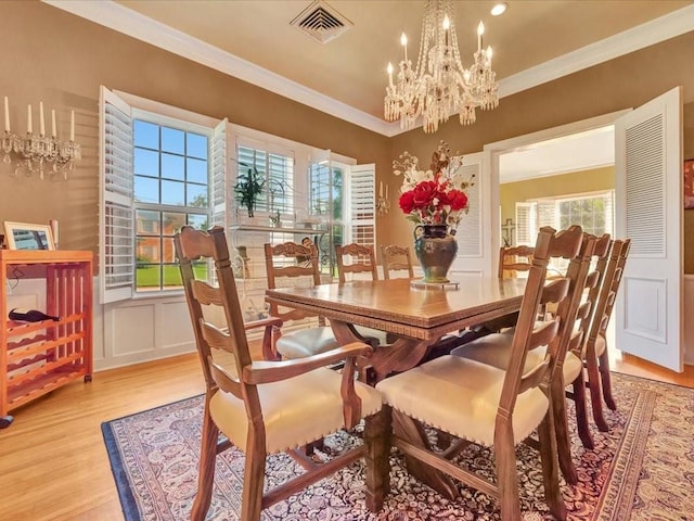 dining room with light wood-type flooring, an inviting chandelier, and crown molding