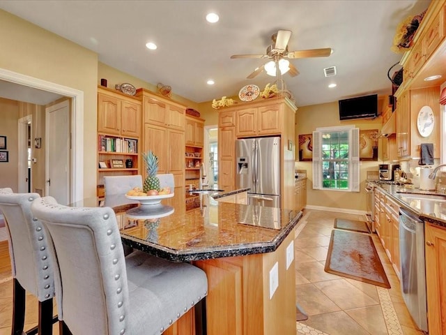 kitchen with sink, stainless steel appliances, dark stone countertops, and a kitchen bar