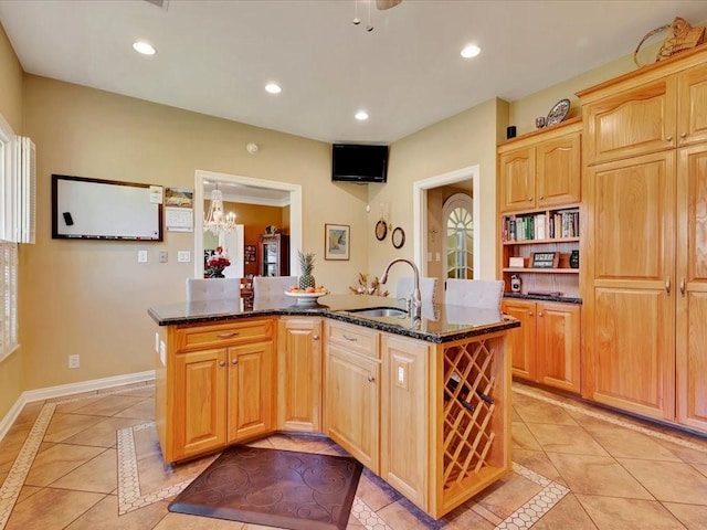 kitchen with sink, dark stone countertops, a kitchen island with sink, and light tile patterned floors