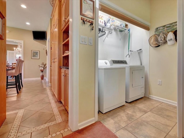 clothes washing area with washer and clothes dryer, an inviting chandelier, and light tile patterned flooring