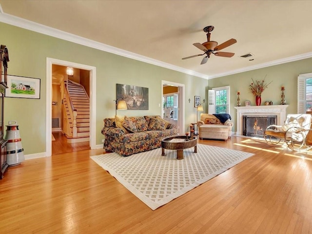 living room featuring light wood-type flooring, ceiling fan, and ornamental molding