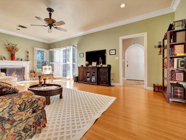 living room with ceiling fan, light wood-type flooring, and crown molding