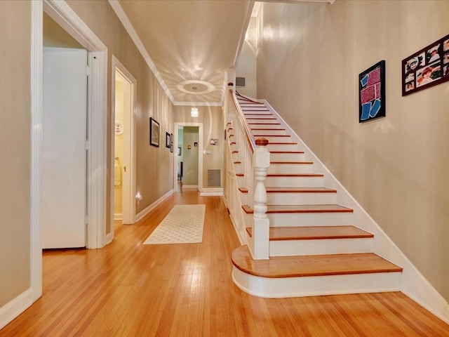 staircase with ornamental molding and wood-type flooring