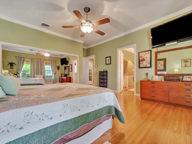 bedroom featuring ensuite bathroom, light wood-type flooring, ceiling fan, and ornamental molding