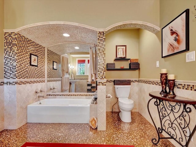 bathroom with tile walls, a washtub, crown molding, and toilet