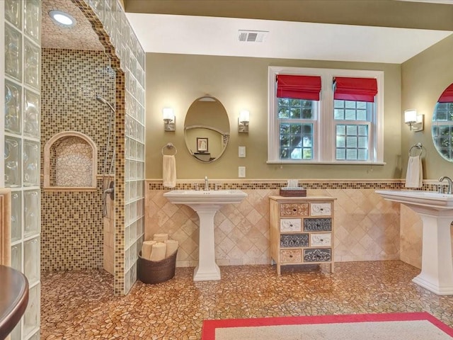 bathroom featuring tile walls, tiled shower, and sink