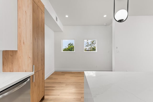 kitchen with light wood-type flooring, dishwasher, light stone counters, and decorative light fixtures