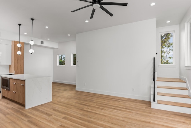 kitchen featuring light hardwood / wood-style floors, ceiling fan, pendant lighting, white cabinets, and oven