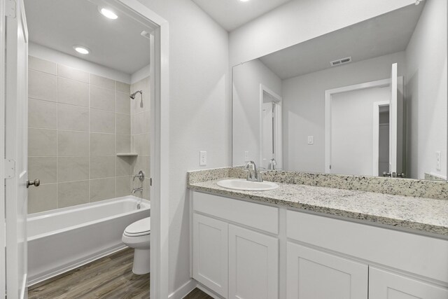 full bath featuring vanity, toilet, bathing tub / shower combination, visible vents, and wood finished floors