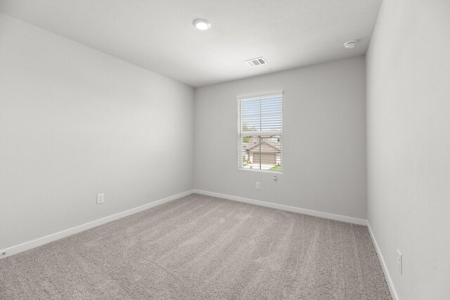 spare room with baseboards, visible vents, and light colored carpet