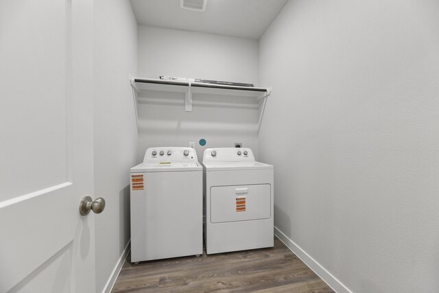 washroom with visible vents, baseboards, laundry area, washing machine and dryer, and dark wood-style floors