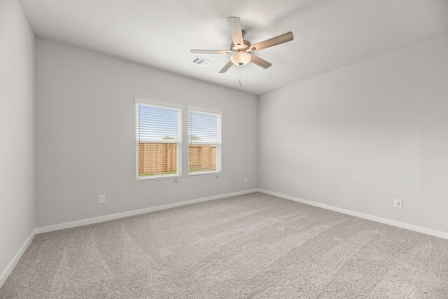 empty room with baseboards, visible vents, carpet, and a ceiling fan