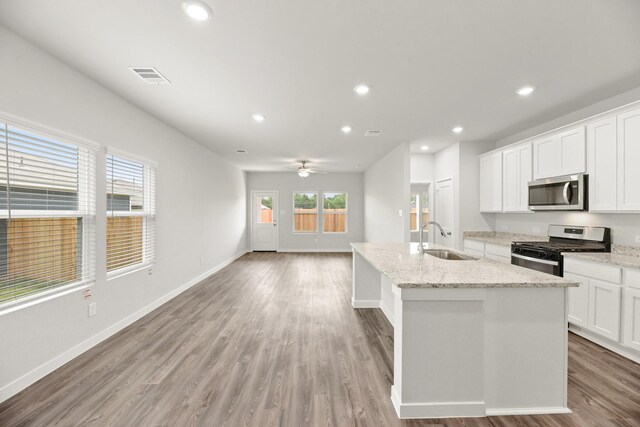 kitchen featuring a sink, appliances with stainless steel finishes, a center island with sink, light wood-style floors, and recessed lighting